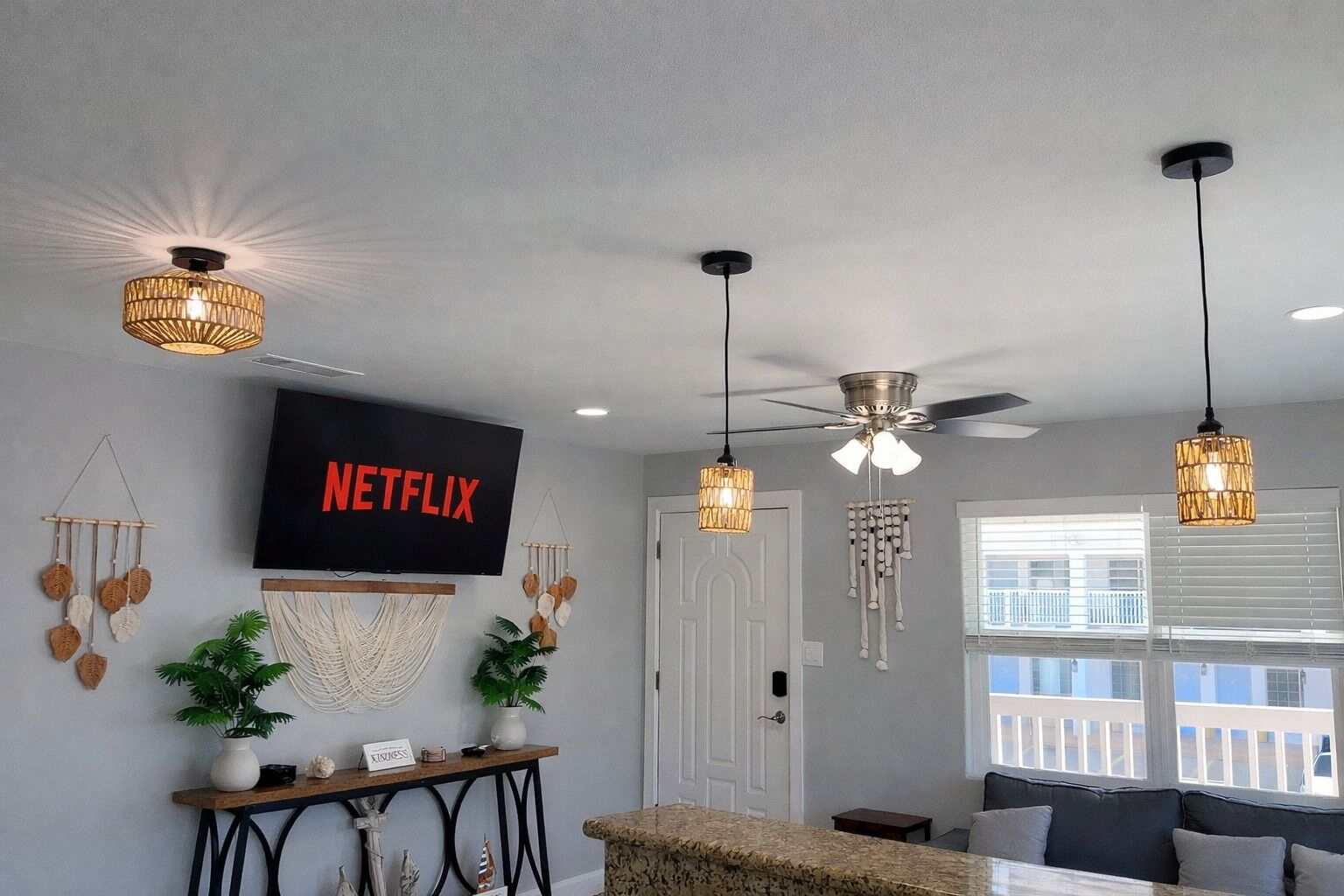 A living room with a TV, ceiling fans, and pendant lights.