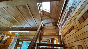 A wooden interior with a staircase, wooden walls, and a hanging decoration. - Mountain pine majesty jibhi  (Banjar)