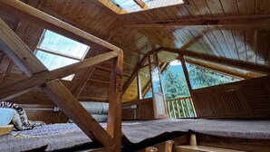 A wooden attic bedroom with skylights, a bed, and a view of trees. - Mountain pine majesty jibhi  (Banjar)