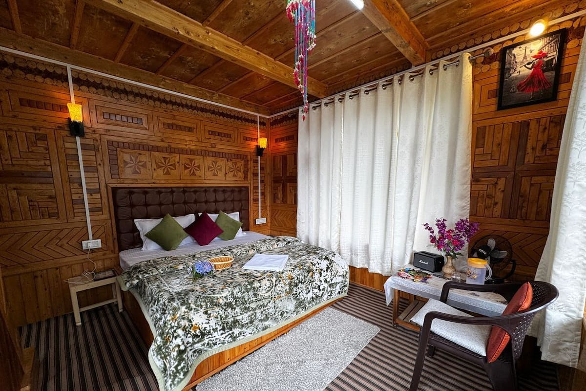 Een gezellige houten kamer met een bed, een tafeltje met een ventilator en een stoel.