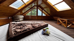 A bedroom with a large bed, wooden beams, and skylights. - Mountain pine majesty jibhi  (Banjar)