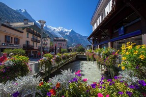 A riverside street with buildings, a bridge, and a mountain in the background. - The Brevent Nest ski in/ski out, Chamonix, France (Chamonix)