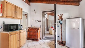 A kitchen with wooden cabinets, a microwave, a coffee maker, and a refrigerator. - Casa Rolè, Lake Maggiore Patio House w/ BBQ, Dormelleto, Italy (Dormelleto)