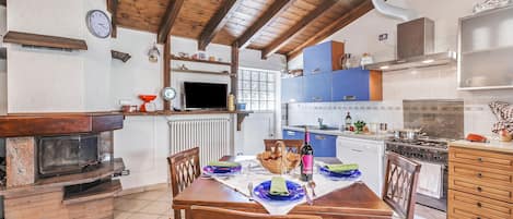 Une cuisine chaleureuse avec une table à manger pour quatre personnes, un four encastré et un téléviseur fixé au mur.