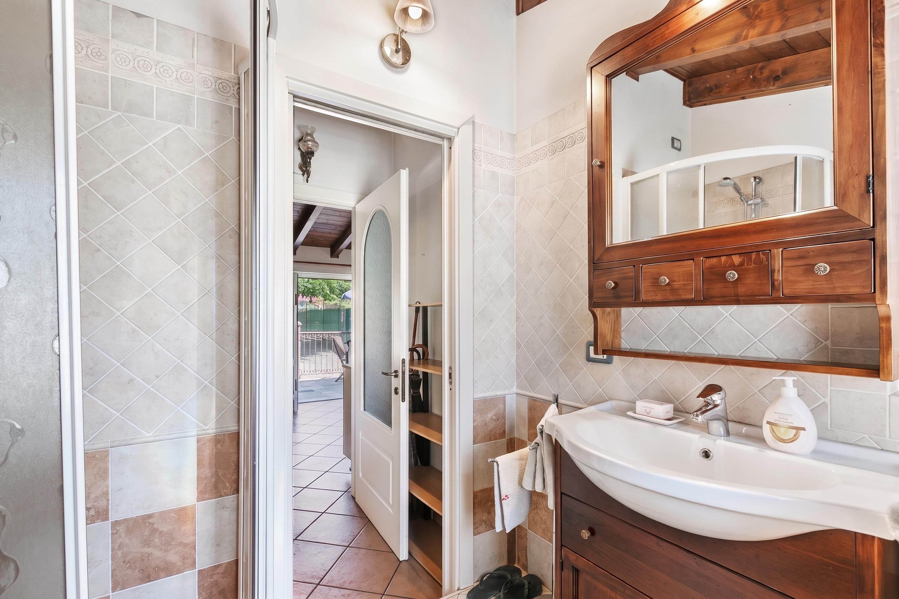 Un bany amb un lavabo blanc, un tocador de fusta i un mirall a sobre.
