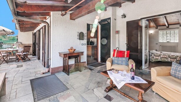 An outdoor patio area with a wooden pergola, a dining table with chairs, and a sofa. - Casa Rolè, Lake Maggiore Patio House w/ BBQ, Dormelleto, Italy (Dormelleto)