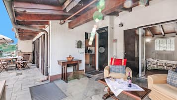 Ein Außenbereich mit einer Holz-Pergola, einem Esstisch mit Stühlen und einer Sitzecke.