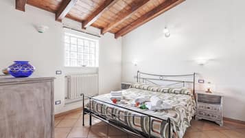 Ein Schlafzimmer mit Bett, Nachttisch, Kommode, Fenster und Heizkörper.