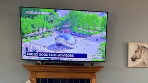 A living room with a fireplace, a television displaying a news channel, a sofa, and a book titled 'Galena Illinois'. - Spacious House with King beds, Fire places, Game Room and Dog friendly. (Galena)