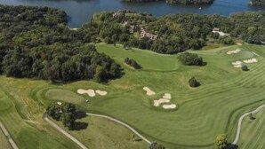 An aerial view of a golf course with multiple bunkers, a water body, and scattered trees. - Spacious House with King beds, Fire places, Game Room and Dog friendly. (Galena)