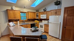 A modern kitchen with wooden cabinets, a central island, a microwave, a refrigerator, and skylights. - Spacious House with King beds, Fire places, Game Room and Dog friendly. (Galena)