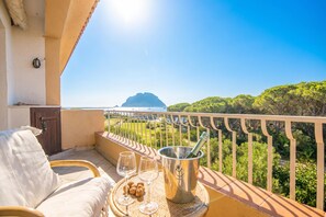 A balcony with a view of a mountain, a bottle of champagne, and glasses on a tray. - Il Vecchio Faro 66, Porto San Paolo, Italy (Porto San Paolo)