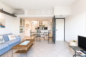 A modern living room with a sofa, coffee table, and dining area. - Il Vecchio Faro 66, Porto San Paolo, Italy (Porto San Paolo)