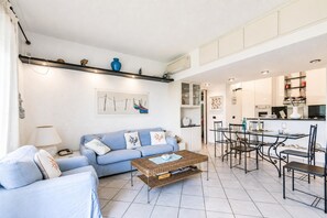 A living room with a sofa, coffee table, and dining area with chairs and a table. - Il Vecchio Faro 66, Porto San Paolo, Italy (Porto San Paolo)