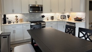 A modern kitchen with white cabinets, a stainless steel stove, a microwave, and a coffee maker. - Spacious Luxury Apartment in Restored Asbury Mansion (Asbury Park)