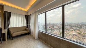 A modern room with a large window, a sofa, and a view of a cityscape. - Enrich Grand Hotel (Bangkok)