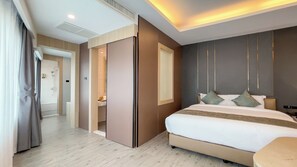 A hotel room with a bed, bedside table, and a view of a hallway. - Enrich Grand Hotel (Bangkok)