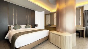 A modern hotel room with a large bed, a vanity with a mirror, and a built-in desk. - Enrich Grand Hotel (Bangkok)