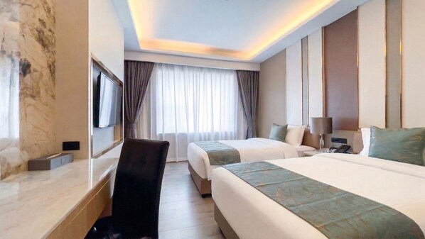 A hotel room with a bed, bedside table, TV, and a desk with a chair. - Enrich Grand Hotel (Bangkok)