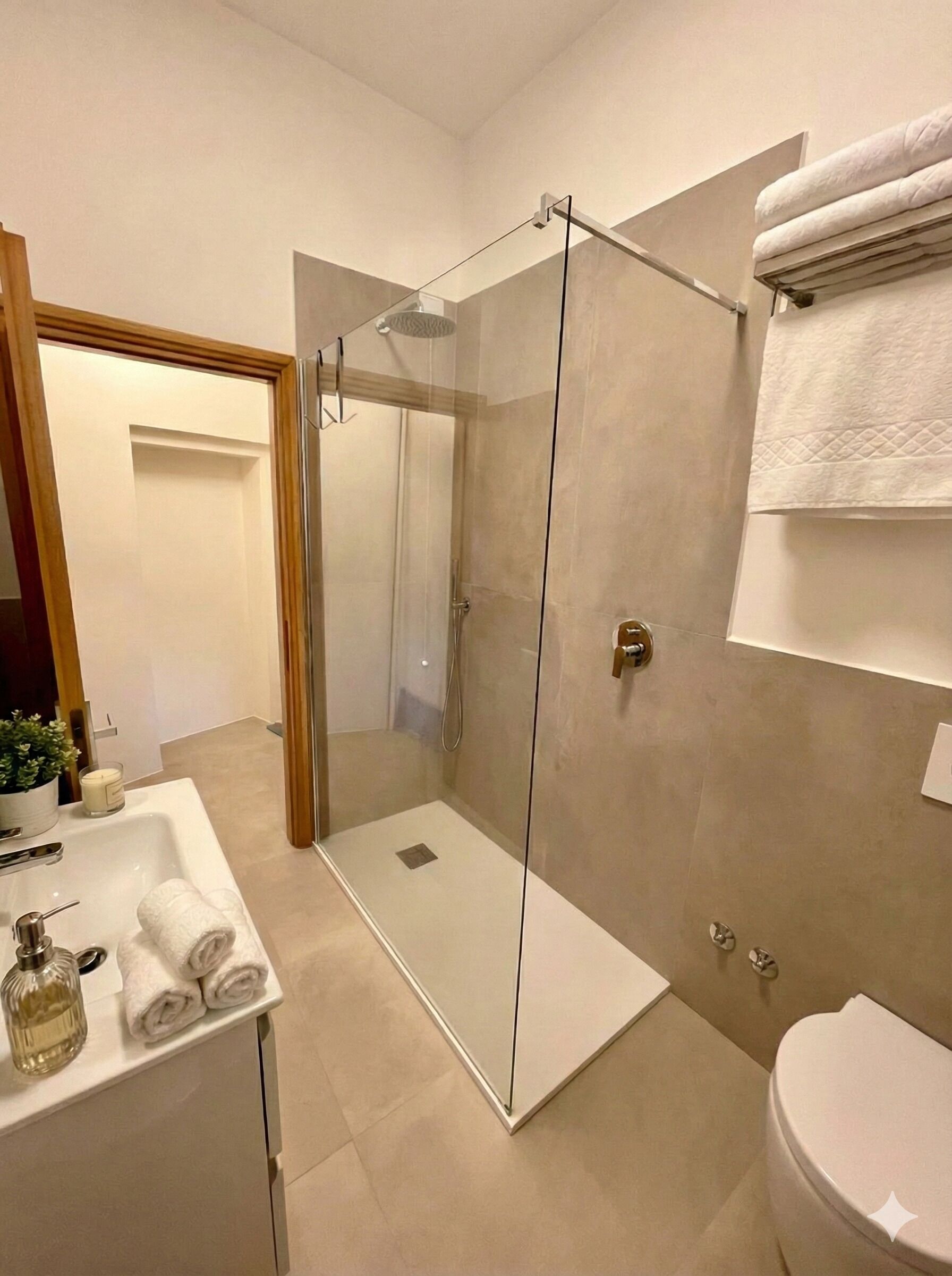 A modern bathroom with a glass-enclosed shower, a white sink with a mirror, and a toilet.