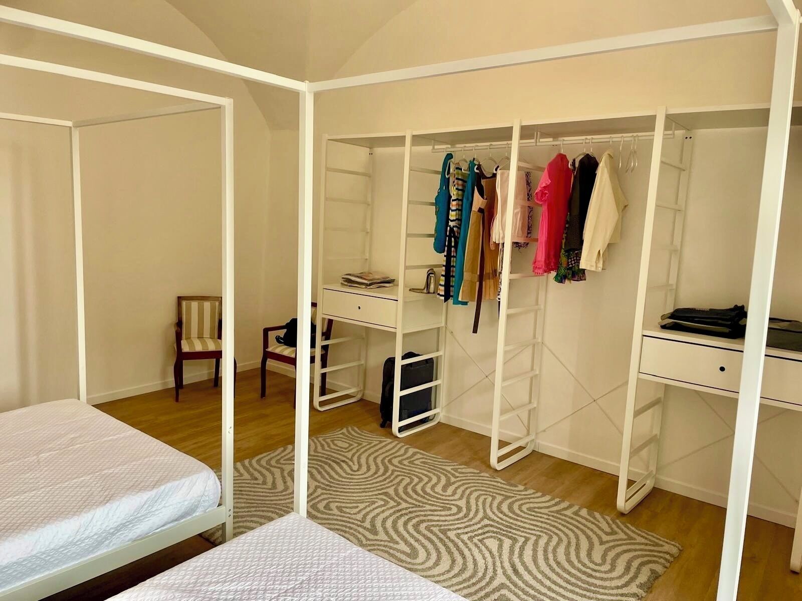 Une chambre à coucher comprenant un lit, un bureau, une chaise, une armoire et un tapis à motifs.