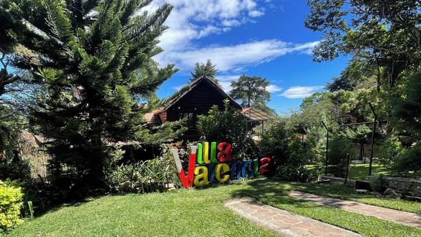 Un jardín con una cabaña de madera y letras coloridas que dicen "LA VIGOR".