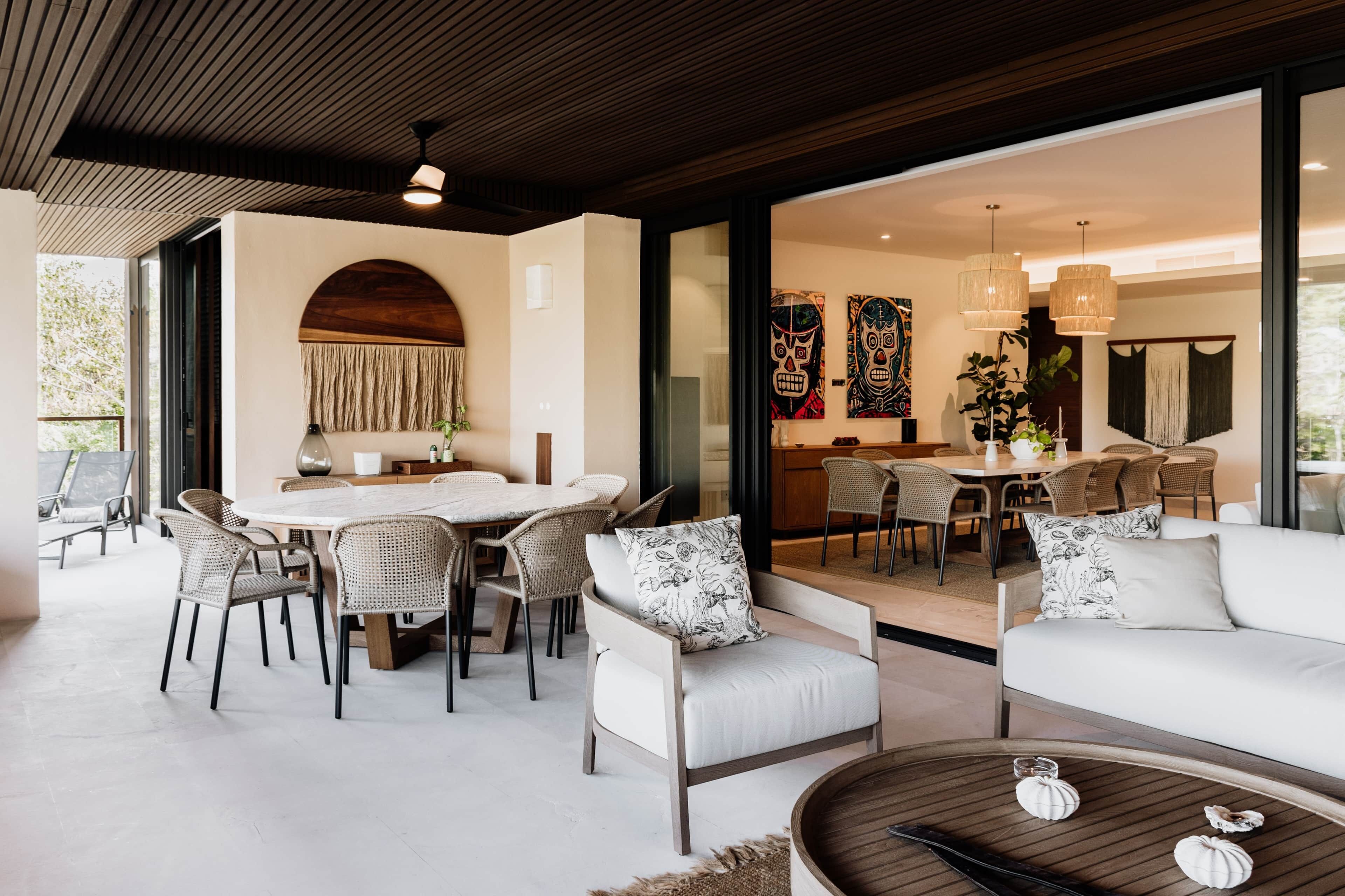 A modern interior with a dining area, sofas, and a large window.