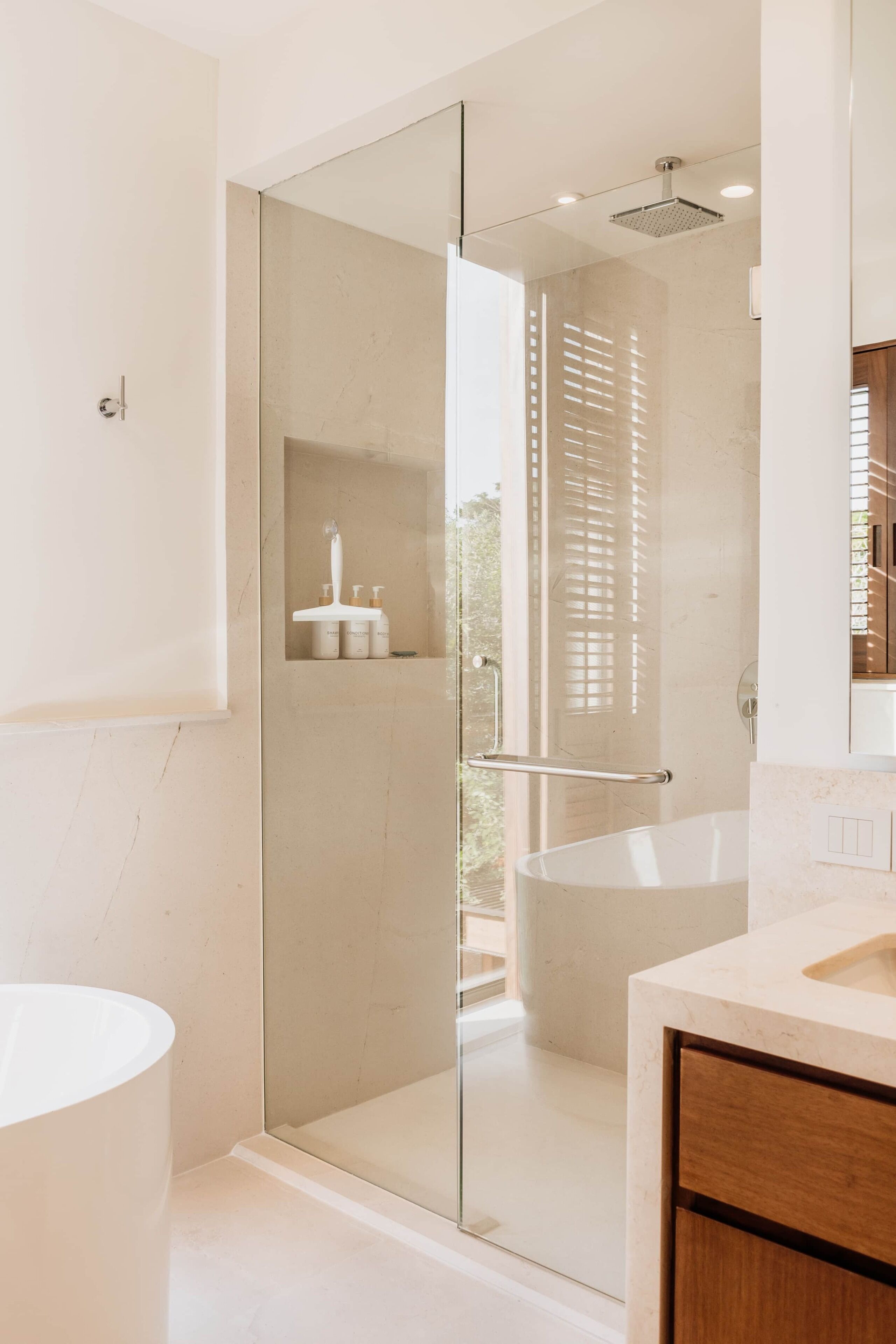 A modern bathroom with a glass-enclosed shower, a freestanding bathtub, and a vanity with a mirror.
