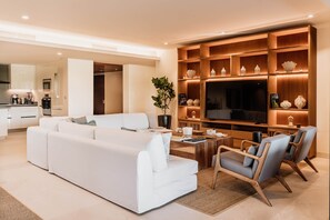 A modern living room with a white sofa, a coffee table, and a TV stand with shelves.