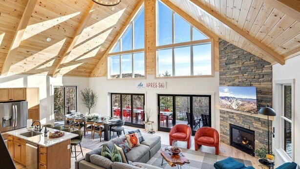 Ein geräumiges Loft mit hoher Decke, großen Fenstern, einem Steinkamin und einer Essecke.