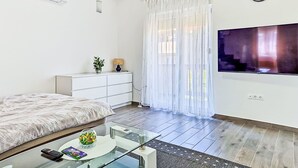 A modern bedroom with a bed, a TV, a small table, and a window with curtains. - Vacation home Sara by Interhome (Zadar)