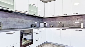 A modern kitchen with white cabinets, a built-in oven, a microwave, and a stainless steel sink. - Vacation home Sara by Interhome (Zadar)