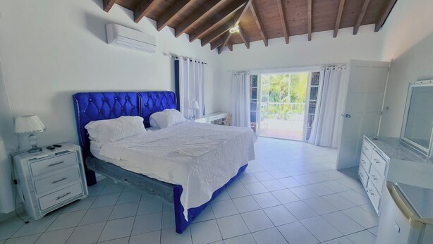 Un dormitorio con cama, mesita de noche, cómoda y ventana con cortinas.