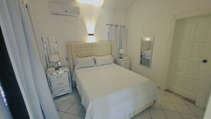 Un dormitorio con cama, mesitas de noche, un espejo y una puerta.