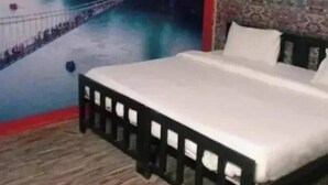 A bedroom with a bed, a wooden headboard, and a cityscape mural on the wall. - Sukhdev Resort Rishikesh (Rishikesh)