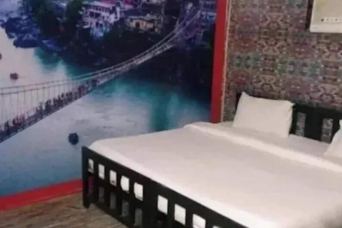 A bedroom with a bed, a wooden headboard, and a cityscape mural on the wall.