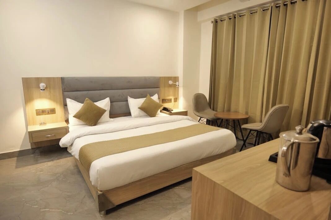 Una camera d'albergo con un letto grande, comodini con lampade, una scrivania e una sedia.