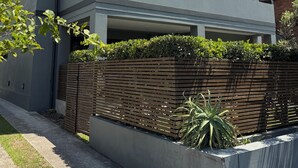 Una casa moderna de dos pisos con techo plano, un balcón y una valla de madera.