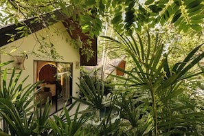 Un bâtiment de style traditionnel, doté d’une façade en bois, entouré d’une végétation luxuriante et d’un jardin bien entretenu.