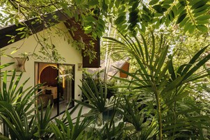 A traditional-style building with a wooden exterior, surrounded by lush greenery and a well-maintained garden.