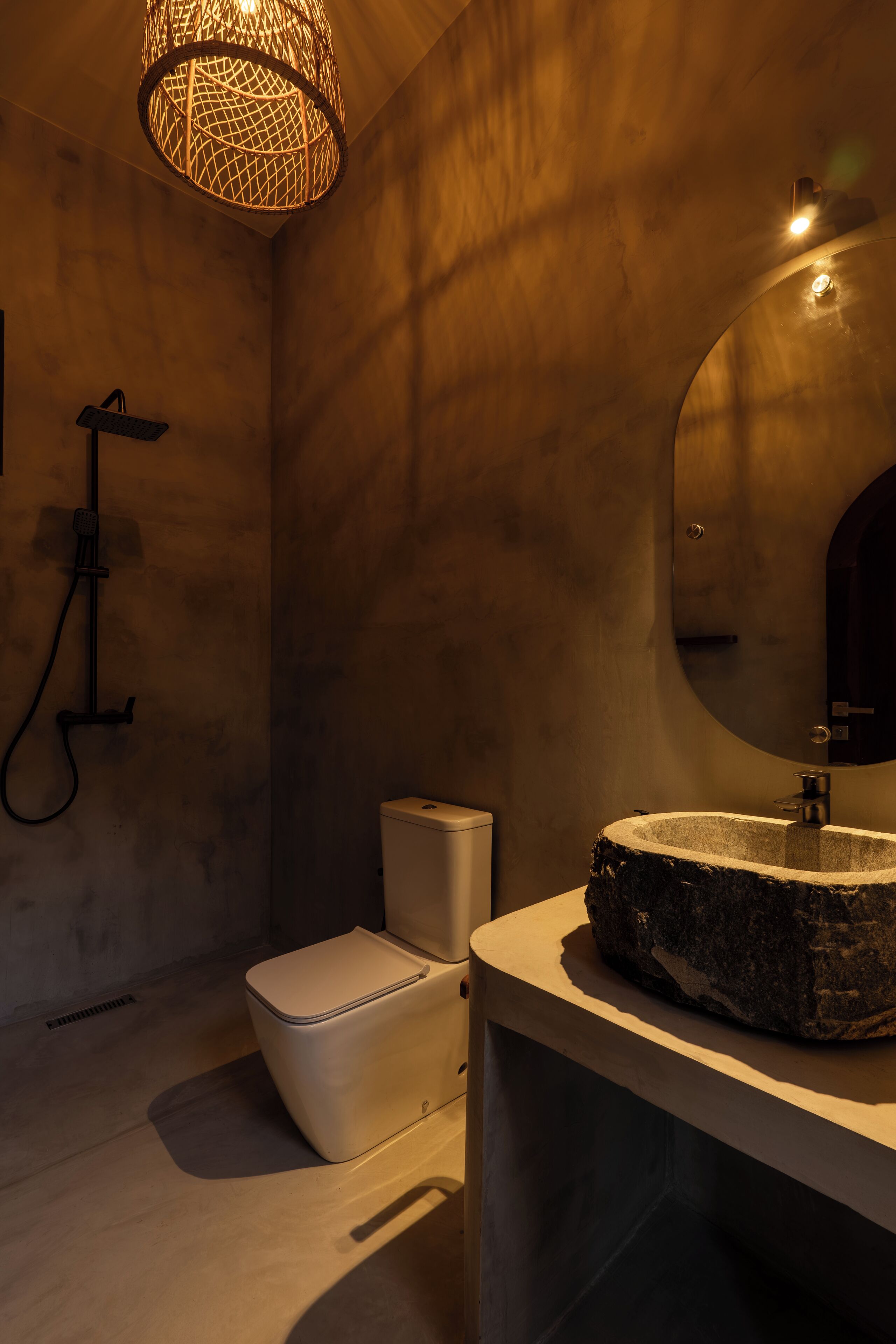 A modern bathroom with a stone sink, a toilet, and a shower.