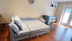A living room with a grey sofa, a small table with a vase, and a blue chair. - Beautiful 1 bedroom suite close to UBC (Vancouver)
