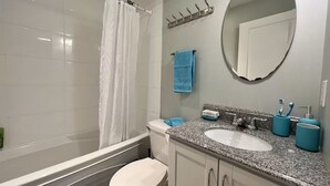 A bathroom with a bathtub, toilet, sink, and a mirror. - Beautiful 1 bedroom suite close to UBC (Vancouver)