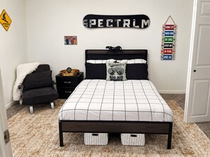 A bedroom with a bed, a nightstand, a chair, and a wall with signs. - Art City Escape - Luxury Swim Spa & Private Entertainment Retreat (Springville)