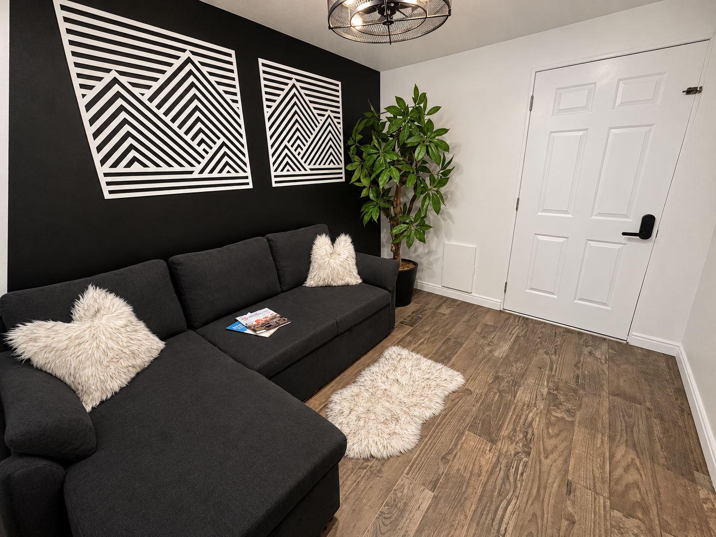 Un salon moderne avec un canapé d’angle, une plante en pot et une porte blanche.