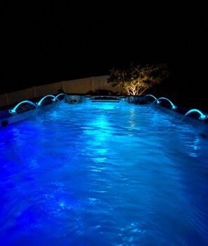 A swimming pool with blue lighting and a tree in the background. - Art City Escape - Luxury Swim Spa & Private Entertainment Retreat (Springville)