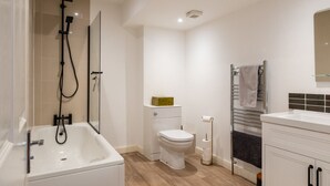 Une salle de bain moderne équipée d’une baignoire, de toilettes et d’une douche.