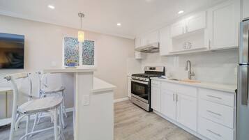 A modern kitchen with white cabinetry, a built-in oven, and a stainless steel refrigerator.