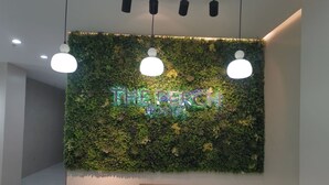 A reception area with a green wall covered in plants and a neon sign that reads "THE PERCH HOTEL". - The Perch Hostel (Olongapo)