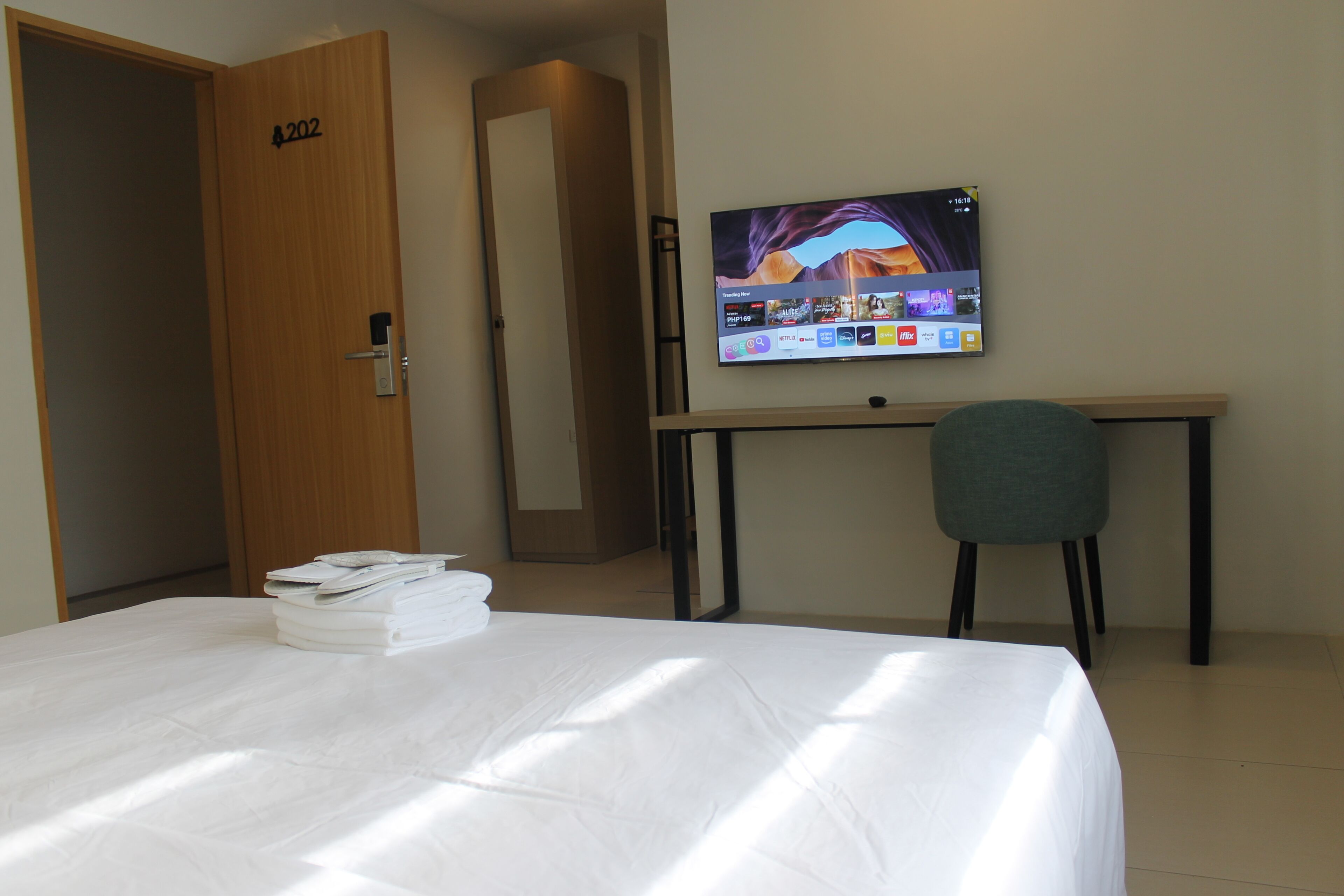Una habitación de hotel con cama, escritorio, televisor y una silla.